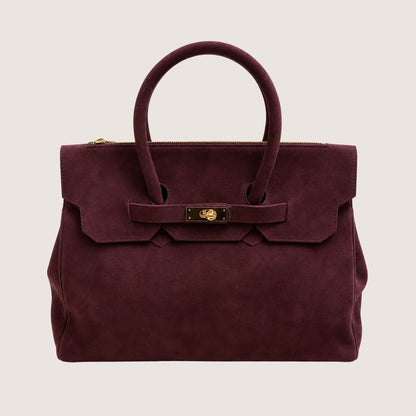 Deep burgundy suede handbag with a gold clasp on a light beige background.