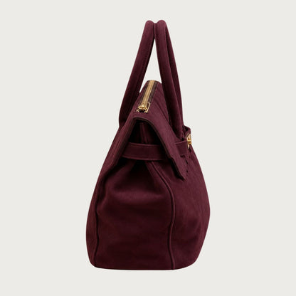 Side view of deep burgundy suede structured handbag with gold zipper detail